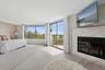 Bedroom featuring access to exterior, a glass covered fireplace, and wood finished floors