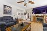 Living area with light wood-finish flooring, a ceiling fan with integrated lighting, and a built-in media console featuring a fireplace insert