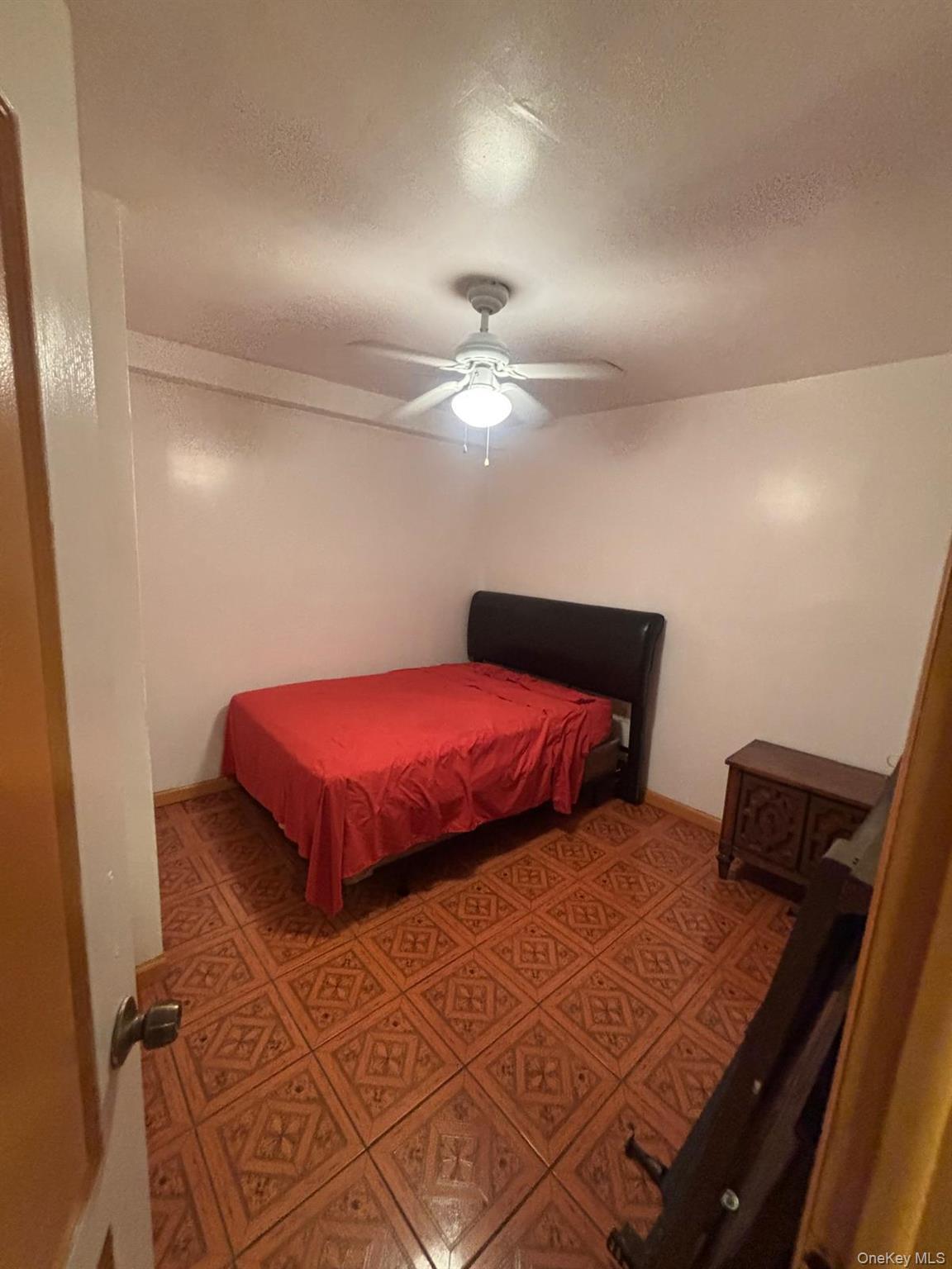 Bedroom with a textured ceiling, a ceiling fan, and light floors