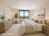 Spacious and sun-filled bedroom featuring a new oversized window showcasing open views of surrounding greenery. The generous layout easily accommodate