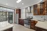 Kitchen featuring appliances with stainless steel finishes, light stone counters, wall chimney exhaust hood, glass insert cabinets, and recessed light