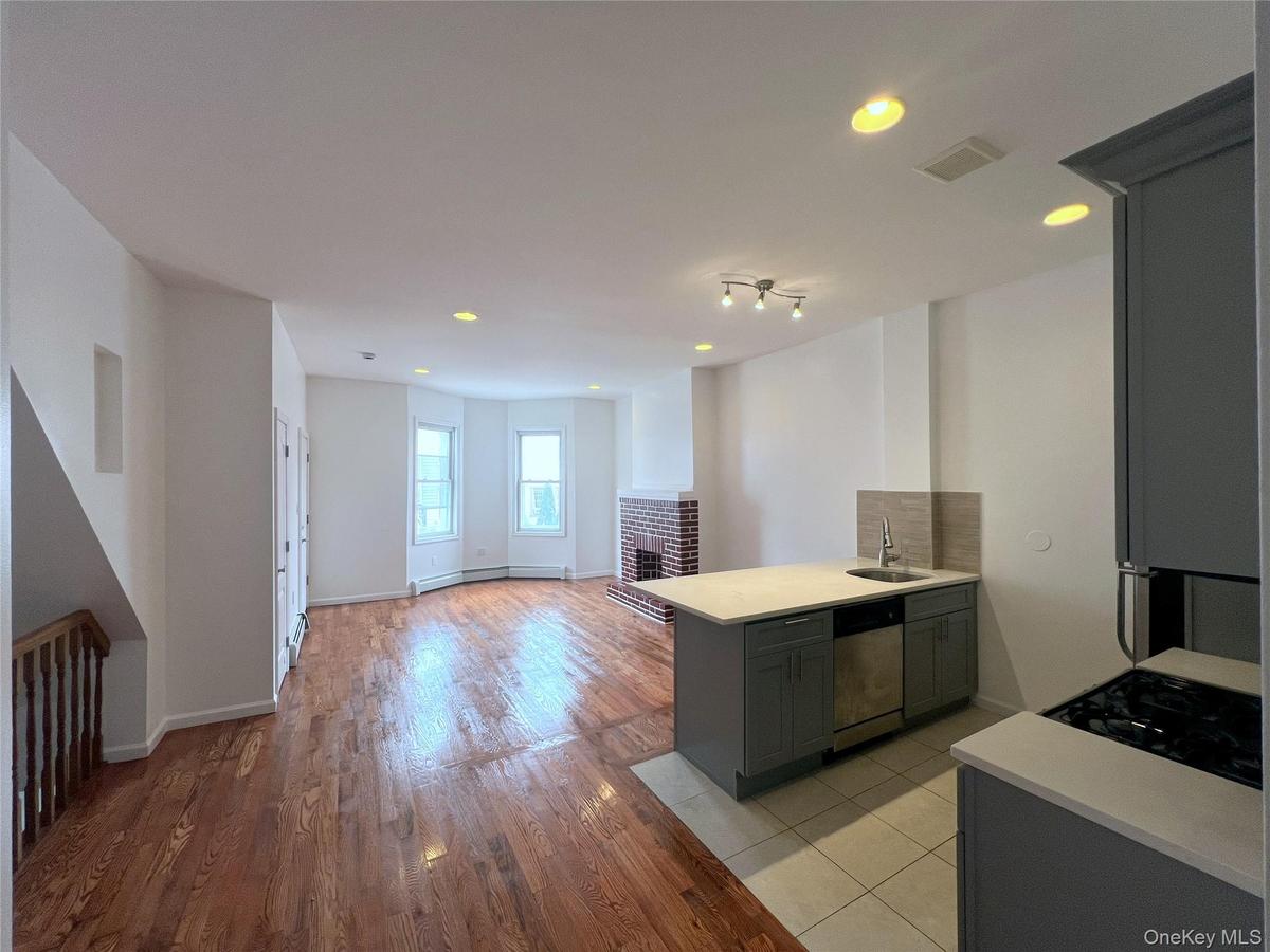 Kitchen with dishwasher, a peninsula, light countertops, a brick fireplace, and recessed lighting