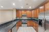 U-shaped kitchen featuring wood cabinetry, dark granite countertops, stainless steel appliances, a tile backsplash, and recessed lighting