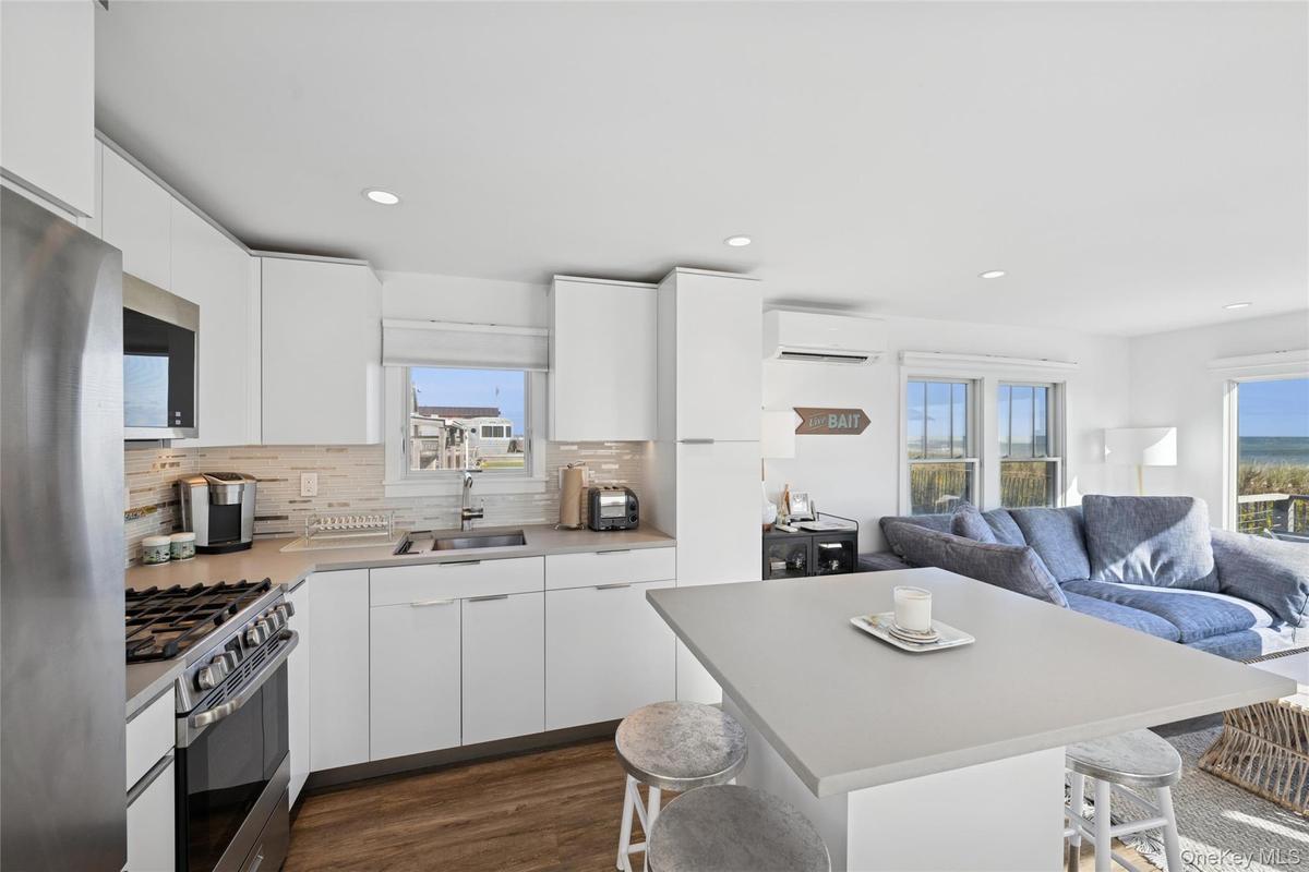 Kitchen with a breakfast bar, white cabinets, stainless steel appliances, modern cabinets, and recessed lighting