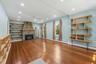 Living area featuring a stone fireplace with a wood mantle, wood-finish flooring, built-in shelving, recessed lighting, and a ceiling fan