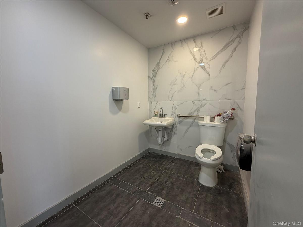 Bathroom with recessed lighting, dark tile patterned floors, and stone wall