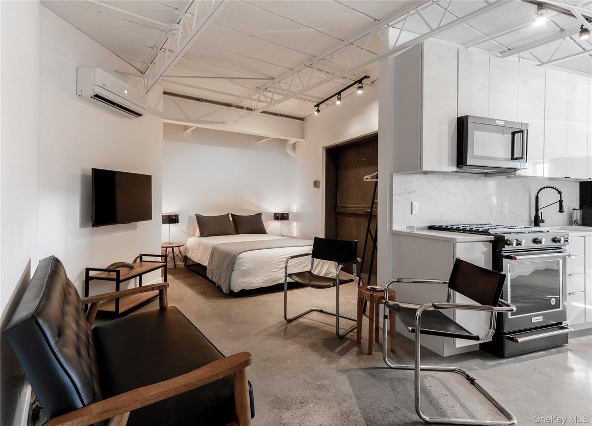 Bedroom featuring track lighting, concrete floors, and a wall mounted AC