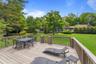 Expansive wood-finish deck with perimeter railing and a gated entry to the yard
