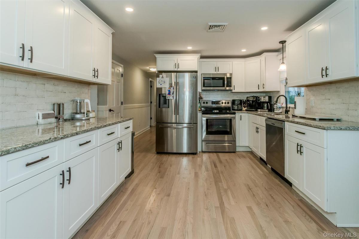 Kitchen featuring white cabinets, stainless steel appliances, light hardwood / wood-style floors, and sink