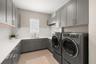 Even the laundry room has been elevated to designer quality with custom wood cabinetry, quartz countertops, tile backsplash, sink with views overlooki