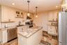 Kitchen featuring a central island with a stone-finish countertop, stainless steel appliances, a subway tile backsplash, recessed lighting, and pendan