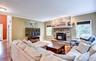 Living area featuring a stone fireplace with hearth and pellet stove, wood flooring, and crown molding