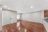 Open-concept living area with polished wood-finish flooring, recessed lighting, crown molding, and a kitchen bar with a granite-style countertop