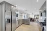 Kitchen featuring decorative backsplash, stainless steel appliances, gray cabinetry, recessed lighting, and open shelves