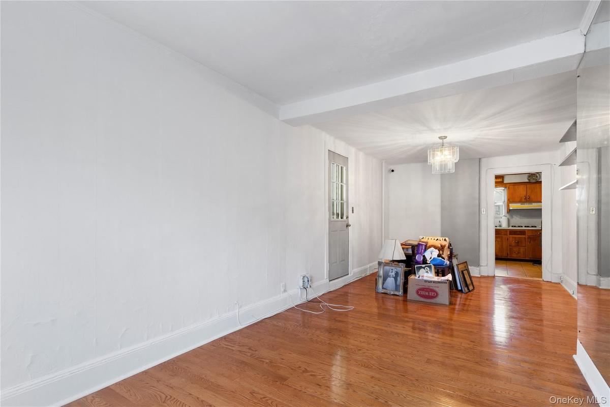 Unfurnished dining area with wood finished floors, a chandelier, and beam ceiling
