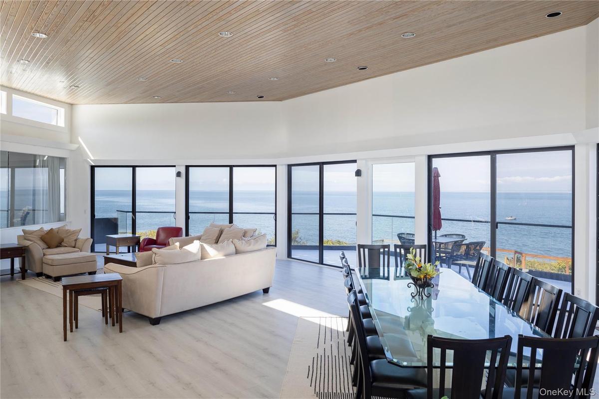 Dining room featuring a water view, light wood-style flooring, and a towering ceiling