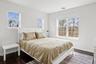 Bedroom with dark wood-style flooring, baseboards, and visible vents