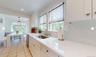 Kitchen with dishwasher, sink, white cabinets, and decorative light fixtures