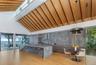 Kitchen with modern cabinets, high vaulted ceiling, a kitchen bar, light stone countertops, and light wood finished floors