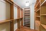 Custom walk in closet system featuring wood-finish shelving and chrome hanging rods