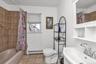 Full bathroom with shower / bath combo, light tile patterned flooring, a baseboard radiator, and vanity