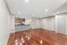 Open-concept living space featuring wood-finish flooring, recessed lighting, crown molding, a kitchen bar with a stone finish, and light wood cabinetr