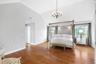 Oversized with vaulted ceiling with crown molding, wood-finish flooring, multiple windows, and a chandelier