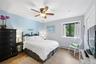Bedroom featuring wood-finish flooring, a ceiling fan with light fixture, and a window with exterior tree scenery