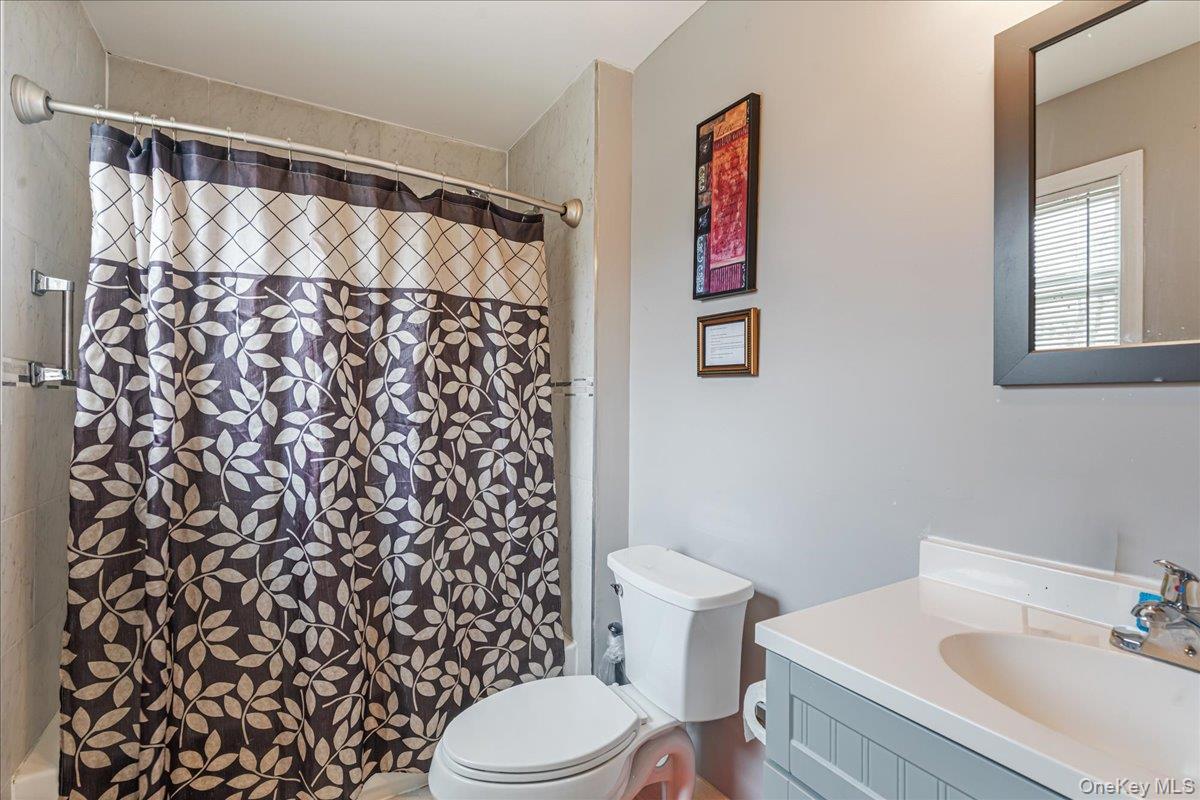 2 nd Floor Bathroom featuring a shower with tile surround, a built-in vanity with a white countertop and integrated sink, a framed mirror, and a toile