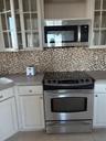 Kitchen with stainless steel appliances, glass insert cabinets, white cabinets, and light tile patterned flooring