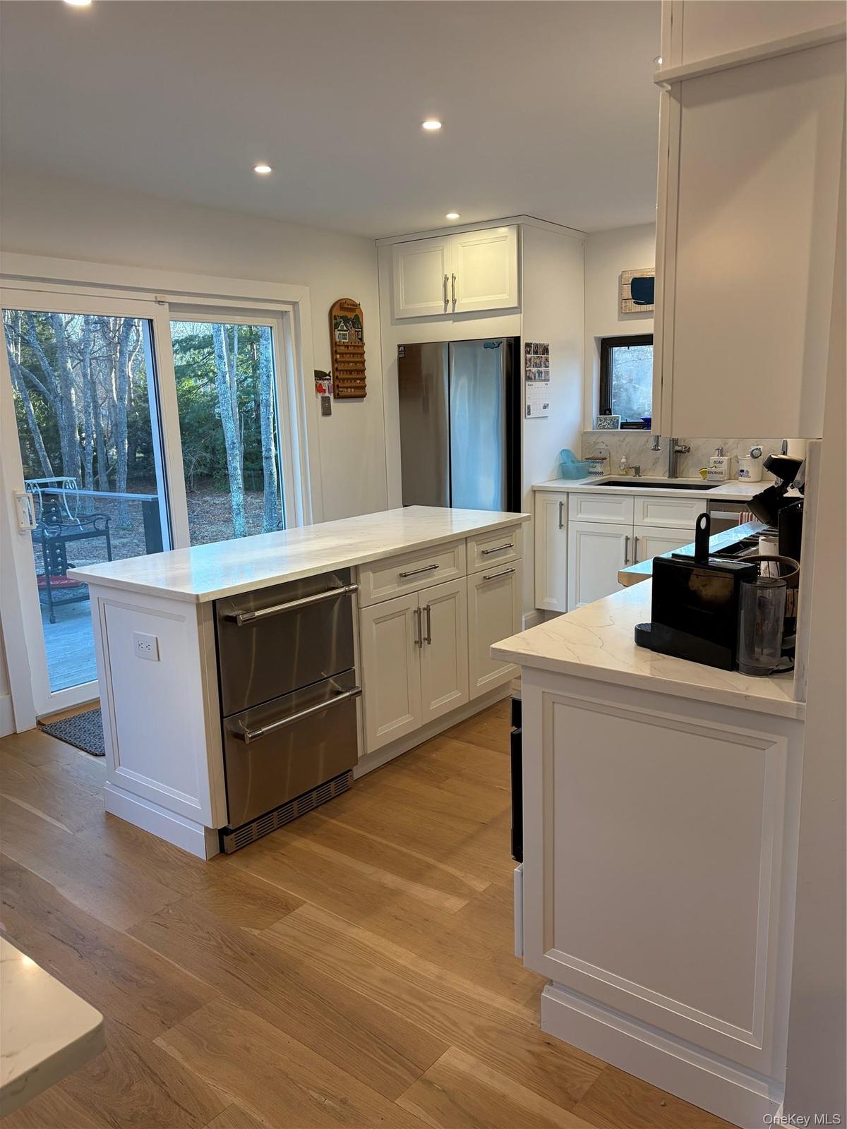 Kitchen with a kitchen island, white cabinets, light wood finished floors, recessed lighting, and stainless steel appliances