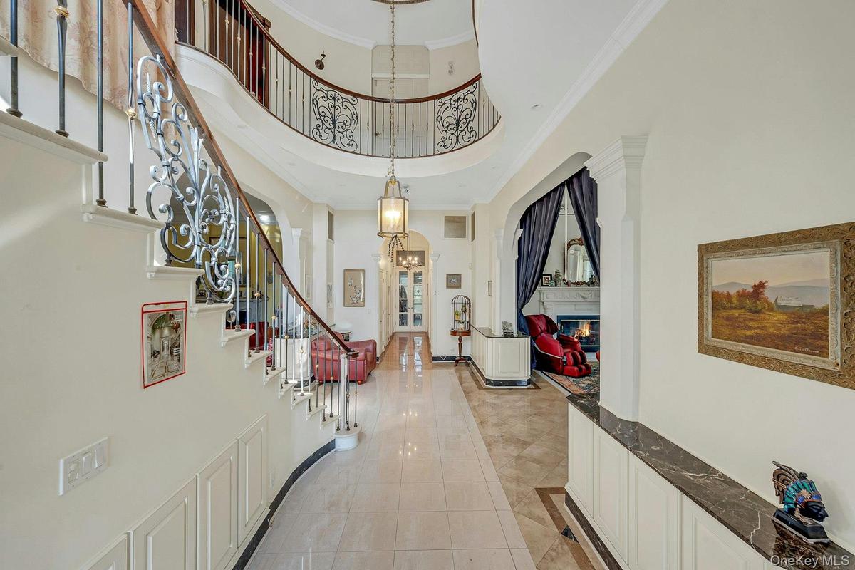 Entryway with a high ceiling, a glass covered fireplace, stairs, light tile patterned flooring, and ornamental molding
