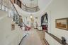 Entryway with a high ceiling, a glass covered fireplace, stairs, light tile patterned flooring, and ornamental molding