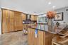 Kitchen featuring a kitchen breakfast bar, paneled fridge, backsplash, stone tile floors, and wall chimney exhaust hood