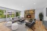 Living room with recessed lighting, light wood-style floors, and a stone fireplace (virtually staged)