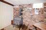 Interior space featuring a brick accent wall, a wood-burning stove on a raised stone hearth, and a wood-finish ceiling beam