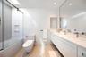 Bathroom featuring tile walls, combined bath / shower with glass door, vanity, and dark speckled floor