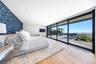 Bedroom featuring expansive windows, light wood-type flooring, access to outside, wallpapered walls, and an accent wall