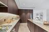 Kitchen featuring light countertops, stainless steel gas stovetop, dark brown cabinetry, a sink, and modern cabinets