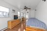 Bedroom with a baseboard radiator, ceiling fan, light wood-style floors, a closet, and a wall unit AC