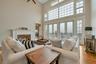 Living room with french doors, ceiling fan, light wood-type flooring, a towering ceiling, and a fireplace