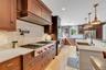 Kitchen featuring tasteful backsplash, light stone counters, appliances with stainless steel finishes, hanging light fixtures, and light wood-type flo