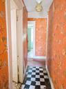 Hallway featuring checkerboard tile flooring, ornate flush-mount ceiling light fixture, and patterned wallpaper