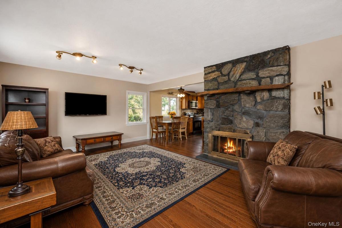 Living area featuring a stone fireplace with a wood mantle, wood-finish flooring, and recessed ceiling lighting
