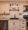 Cream-toned cabinetry with contrasting hardware, granite countertops, subway tile backsplash, and stainless steel appliances