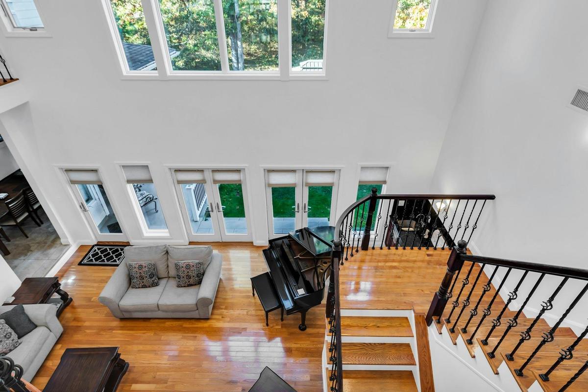 Living room with a high ceiling, french doors, hardwood / wood-style flooring, and stairs