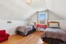 Bedroom featuring vaulted ceiling, radiator heating unit, wood finished floors, wood walls, and a chandelier