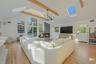 Living room featuring beamed ceiling, light hardwood / wood-style flooring, plenty of natural light, and a notable chandelier