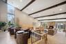 Vaulted ceiling with exposed wood beams, floor-to-ceiling window, wood-finish flooring, stone fireplace, and recessed lighting