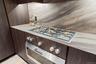 Kitchen with light countertops, cooktop, and dark brown cabinetry